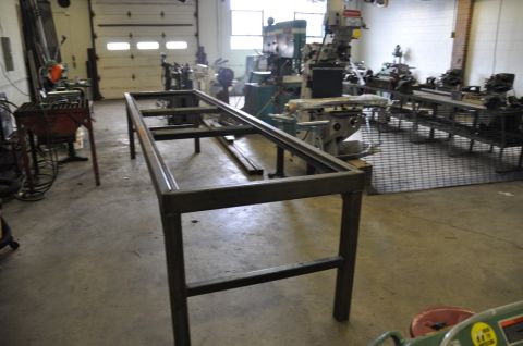 1996 Ford Bronco - A metal table frame sits in the foreground of a workshop filled with various industrial machines.