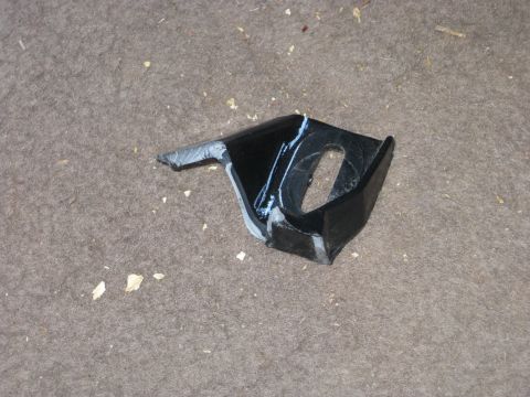1995 Ford Bronco - A close-up view of a single black metal bracket resting on a textured floor.