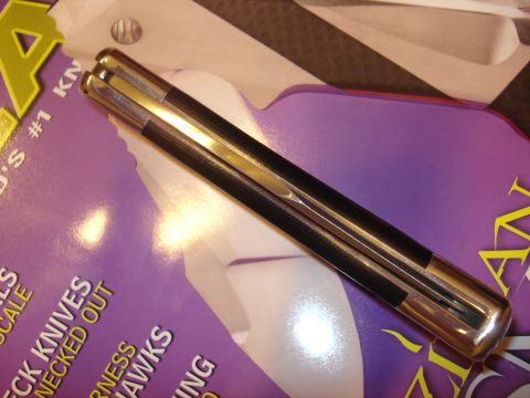 2000 Ford Crown Victoria - A closed folding knife with a black handle and polished metal accents is shown on top of a magazine.