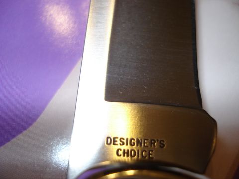 2000 Ford Crown Victoria - Close-up of a knife blade showing the text "DESIGNER'S CHOICE" stamped into the metal.