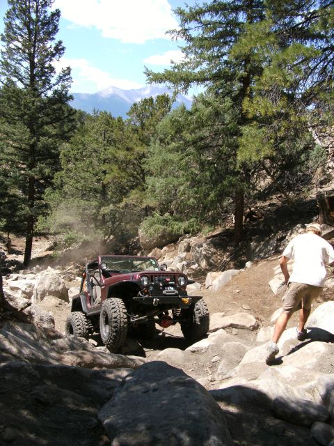 1995 Ford Bronco - A Jeep Wrangler tackles a challenging off-road course with steep inclines and large rocks.