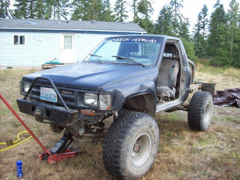 1985 Toyota Pickup/SR5 - This heavily modified 1985 Toyota Pickup features oversized off-road tires and a custom front bumper, suggesting it's built for terrain.