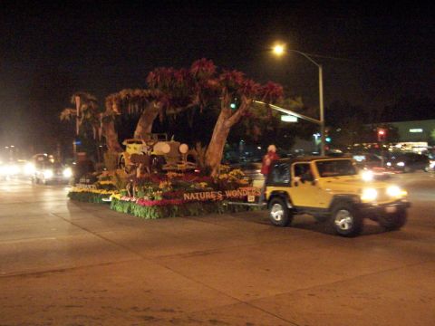 1990 Ford Bronco - A yellow Jeep Wrangler is seen towing a float during a nighttime parade event, with "NATURE'S WONDERS" visible on the float.