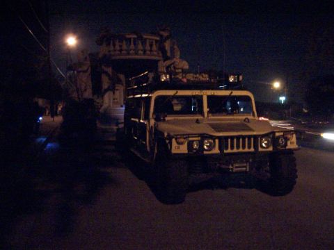 1990 Ford Bronco - A Humvee is parked on a street at night, illuminated by streetlights and its own headlights.