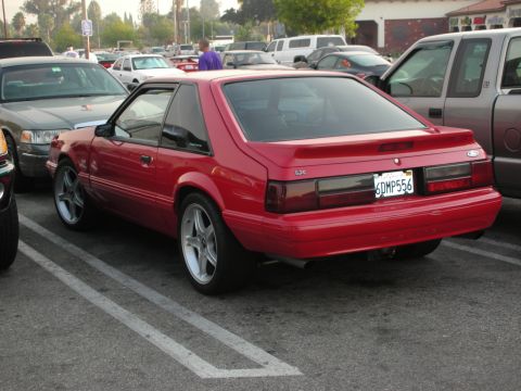 1998 Ford Crown Victoria - A red Ford Mustang is parked in a lot, with other vehicles visible around it.