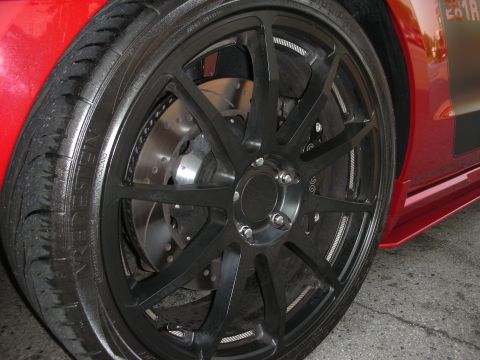 1998 Ford Crown Victoria - Close-up of a red car's wheel, black aftermarket rims and performance brakes.