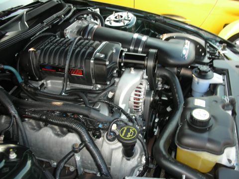 1998 Ford Crown Victoria - Close-up of a supercharged engine bay, with a yellow car in the background.