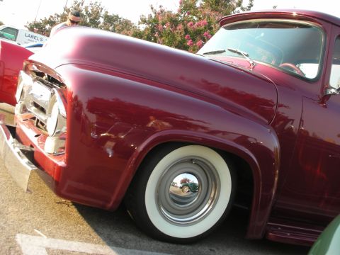 1998 Ford Crown Victoria - A classic maroon pickup truck is parked on pavement, with trees and a white truck in the background.
