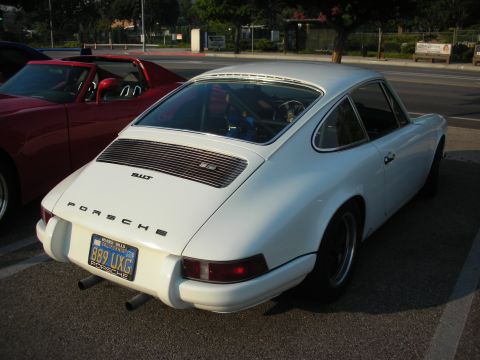 1998 Ford Crown Victoria - A white Porsche 911 is parked next to a red car, showing its rear end and a roll cage inside.