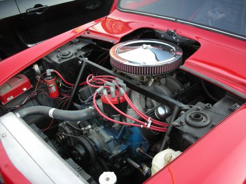 1998 Ford Crown Victoria - The engine bay of a red car is shown, with a black car visible in the background.