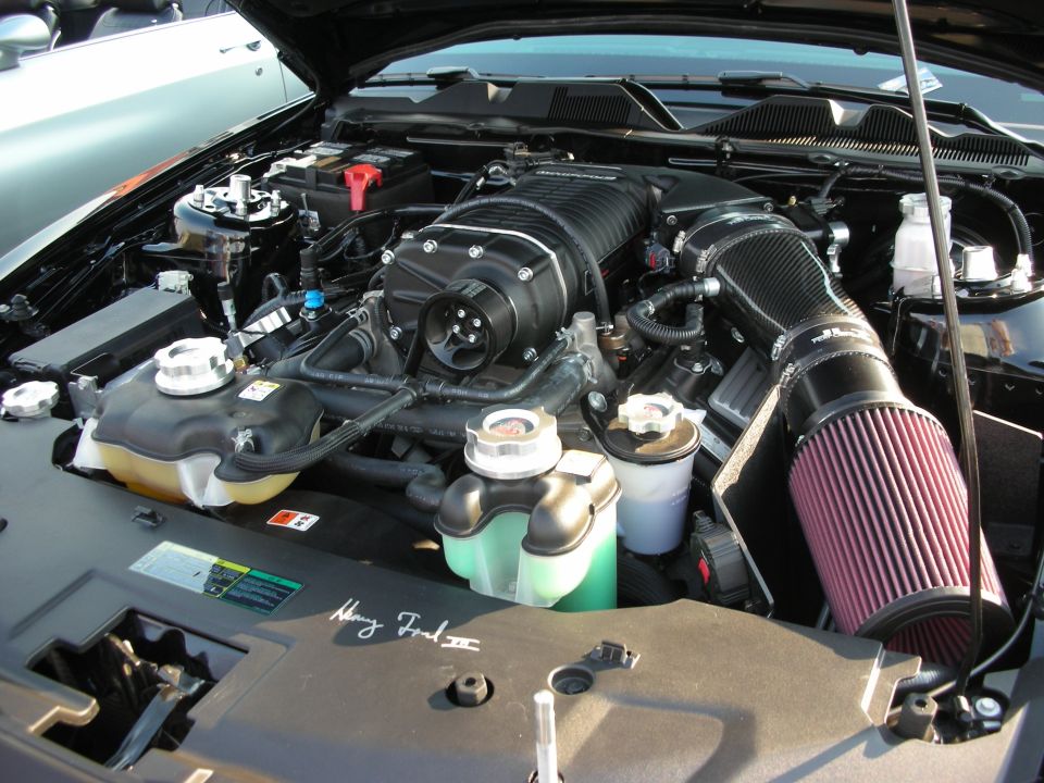 Close-up of a supercharged V8 engine with a large black supercharger and red air filter