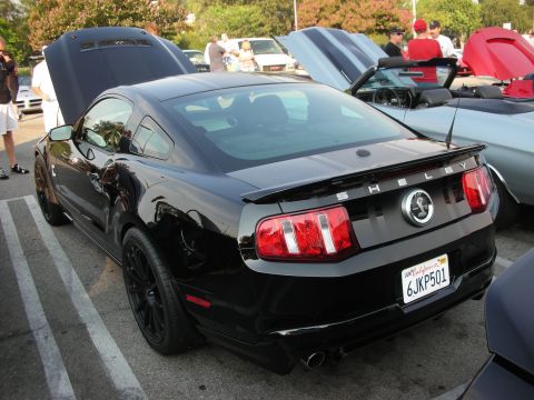 1998 Ford Crown Victoria - A black Ford Mustang Shelby is parked with its hood open, alongside other vehicles.