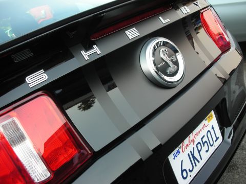 1998 Ford Crown Victoria - The rear of a black Shelby GT500 features racing stripes and the iconic cobra emblem.