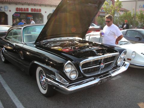 1998 Ford Crown Victoria - A black 1957 Chrysler 300C is displayed with its hood open, revealing the engine, at a car meet.