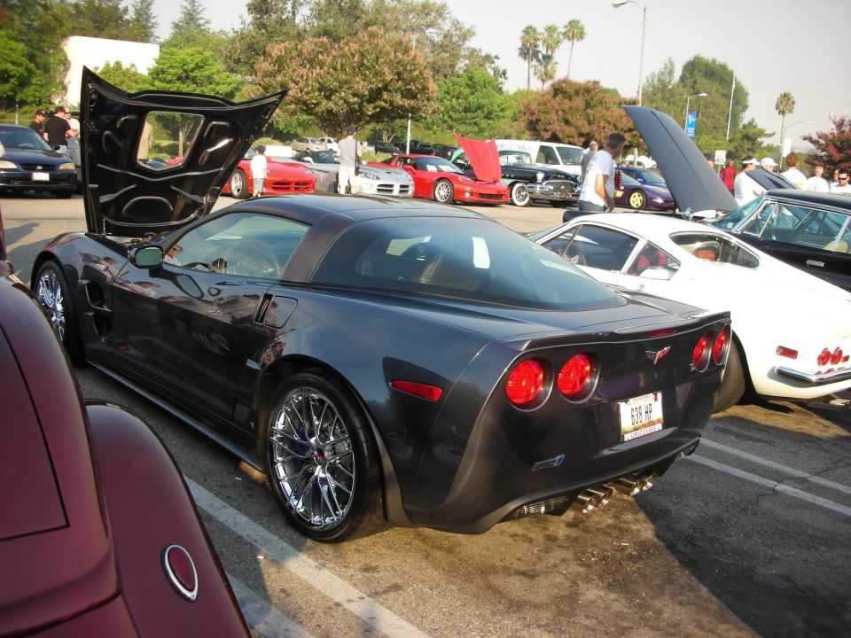 Dark gray Chevrolet Corvette C6 with hood open, parked at an outdoor car meet