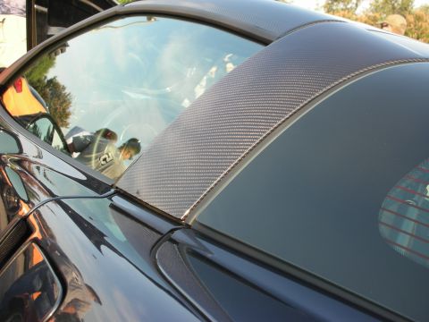1998 Ford Crown Victoria - A close-up view of a dark blue sports car, highlighting its carbon fiber roof pillar and tinted windows.