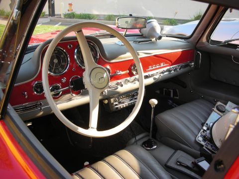 1998 Ford Crown Victoria - The interior of a classic red Mercedes-Benz 300 SL features a white steering wheel and dashboard with prominent "300 SL" badging.