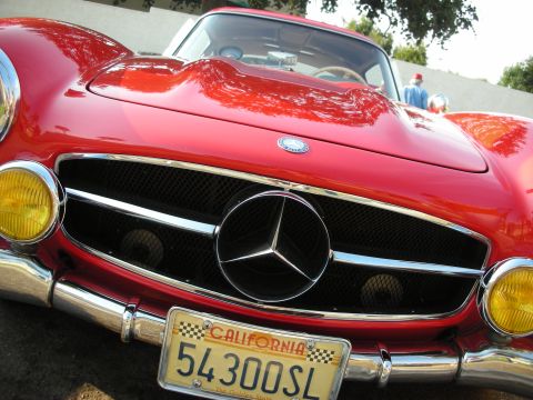 1998 Ford Crown Victoria - A classic red Mercedes-Benz 300SL Gullwing is shown from the front, its iconic grille and yellow headlights.