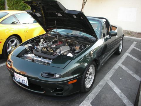 1998 Ford Crown Victoria - Green Mazda Miata with engine exposed, parked next to a yellow Ferrari.