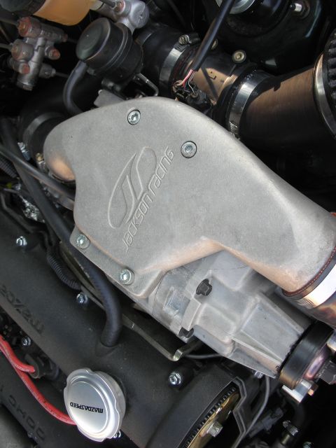 1998 Ford Crown Victoria - Close-up of engine components including a Jackson Racing supercharger and Mazdaspeed oil cap.