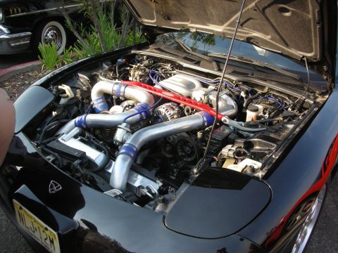 1998 Ford Crown Victoria - The engine bay of a black car is open, revealing its twin turbochargers and a red strut bar.