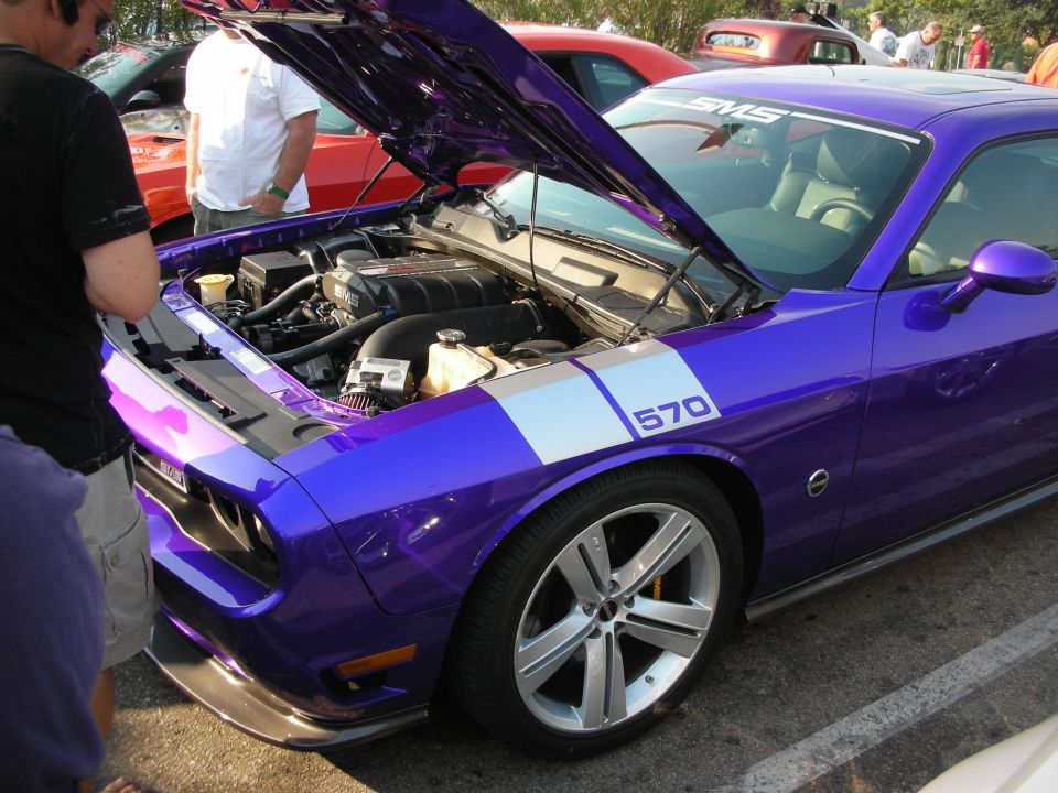 Purple Dodge Challenger with hood open, showing engine and '570' decal on fender. Other cars visible in background