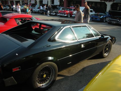 1998 Ford Crown Victoria - A black sports car is parked at a car meet with other vehicles visible.