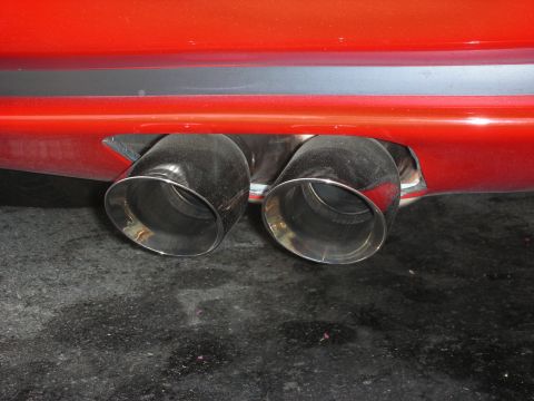 1998 Ford Crown Victoria - Close-up of the rear bumper showing dual exhaust pipes on a red vehicle.