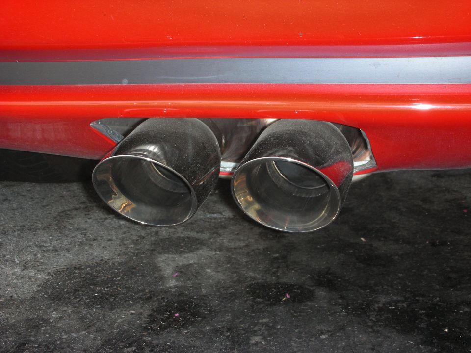 Dual chrome exhaust tips on a red car bumper