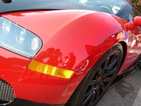 1998 Ford Crown Victoria - The glossy red paint reflects people and the surroundings, obscuring the car's exact make and model.