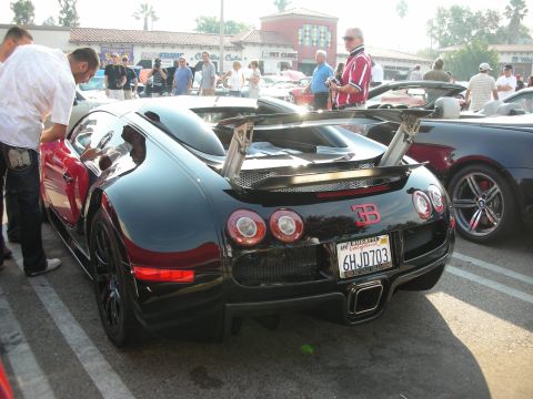1998 Ford Crown Victoria - A black Bugatti Veyron is parked at a car meet, displaying its distinctive rear spoiler and California license plate.