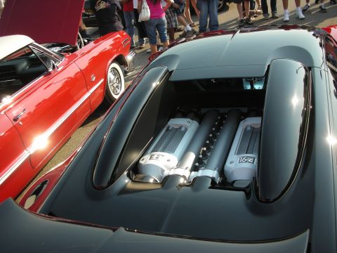 1998 Ford Crown Victoria - Bugatti Veyron's W16 engine bay is exposed, parked beside a vintage red convertible.