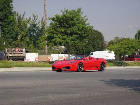 1998 Ford Crown Victoria - A red convertible sports car is seen driving on a road.