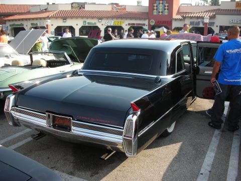 1998 Ford Crown Victoria - A black sedan with distinctive fins and chrome accents is parked at an outdoor event.