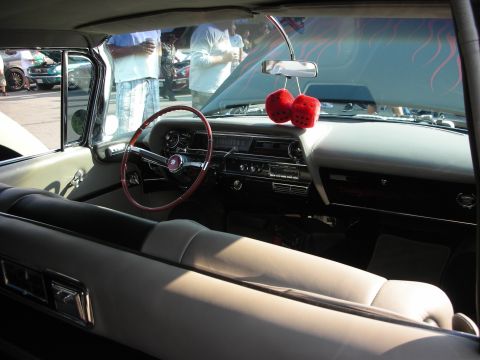 1998 Ford Crown Victoria - A classic car's interior is shown, fuzzy dice and flame decals on the hood, with other vehicles visible outside.