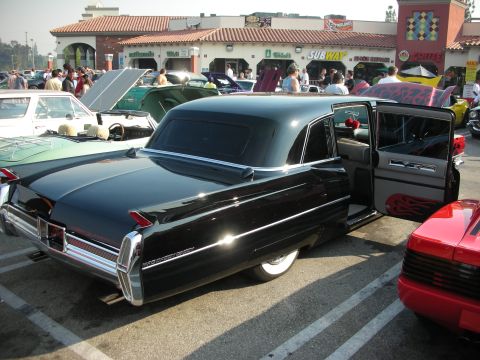 1998 Ford Crown Victoria - A black vintage sedan with its doors open, parked at an outdoor gathering with other vehicles.