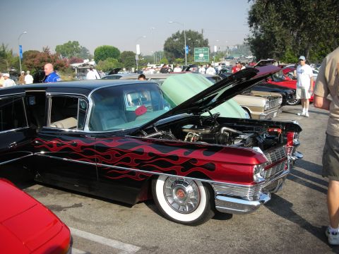 1998 Ford Crown Victoria - A custom hot rod with flame decals and whitewall tires is displayed at an outdoor car event.