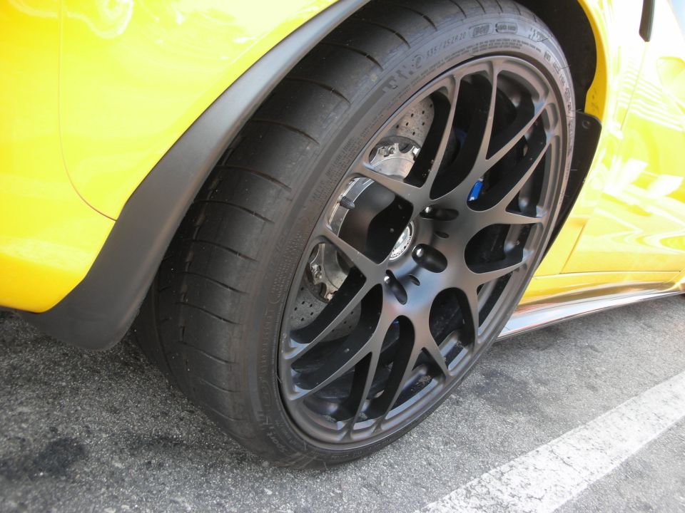 Close-up of a black multi-spoke wheel on a yellow sports car, showing the tire and part of the fender