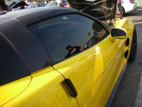 1998 Ford Crown Victoria - A yellow sports car is parked at an outdoor event with its doors open.