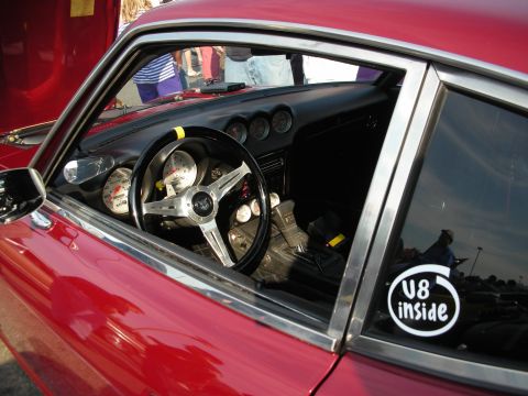 1998 Ford Crown Victoria - The interior of a red car features aftermarket gauges and a V8 inside sticker on the window.