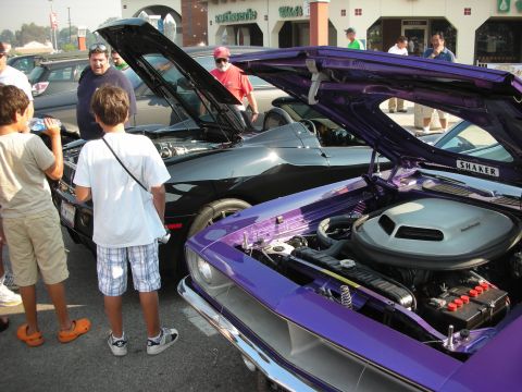 1998 Ford Crown Victoria - Two vintage muscle cars are displayed with their hoods open at an outdoor car show.