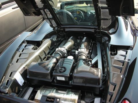 1998 Ford Crown Victoria - The engine bay of a black Ferrari is open, revealing its powerful V8 engine and intricate components.