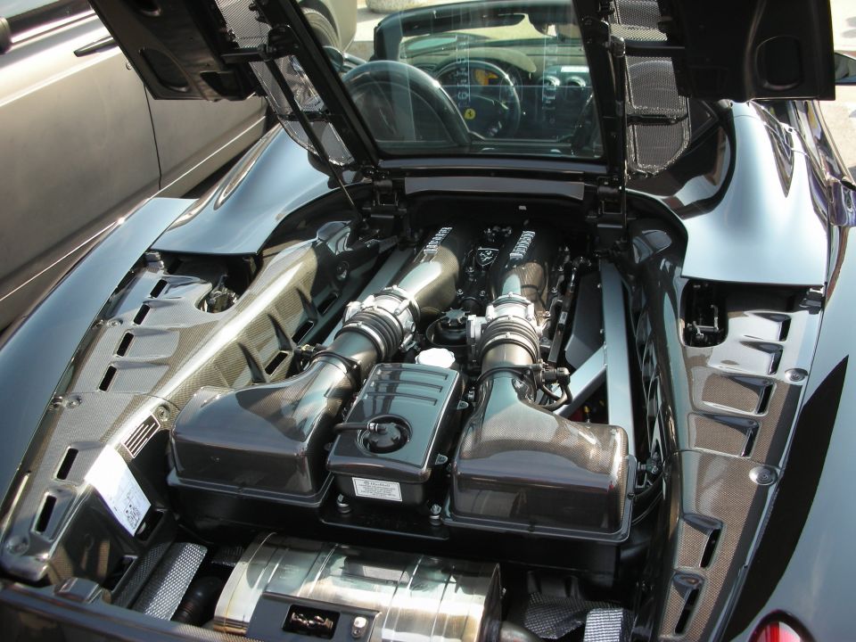 Black Ferrari engine bay with twin intakes and exposed engine components