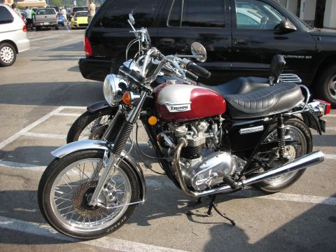 1998 Ford Crown Victoria - A classic Triumph Bonneville 750 motorcycle is parked in a lot, showing its distinctive red and silver paint scheme.
