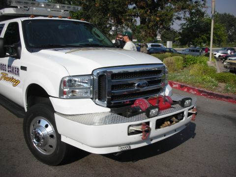 1998 Ford Crown Victoria - A white Ford F-Series truck, likely a commercial towing vehicle, is shown from the front with "ROSS BAKER Towing" visible on the door.