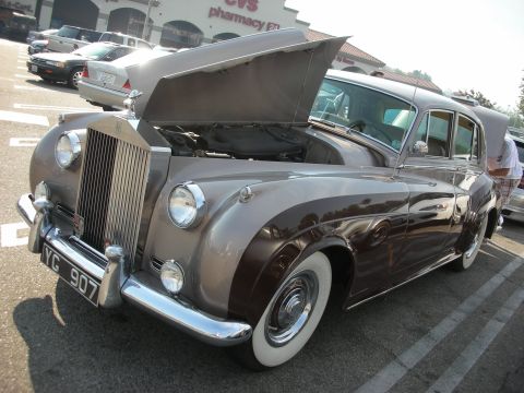 1998 Ford Crown Victoria - A classic Rolls-Royce Silver Cloud from the mid-1950s is displayed with its hood open in a parking lot.