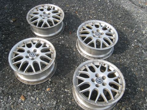 1993 Ford Probe - A set of four Volkswagen alloy wheels is displayed on a gravel surface, showing the brand's emblem on each.