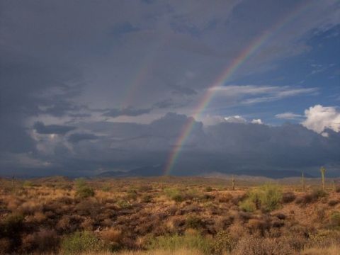 1996 Ford Bronco - A double rainbow arcs across a dramatic sky over a dry desert landscape.