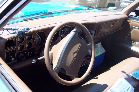 2001 Ford Crown Victoria - The interior of a car shows a tan dashboard with wood grain trim and multiple gauges.