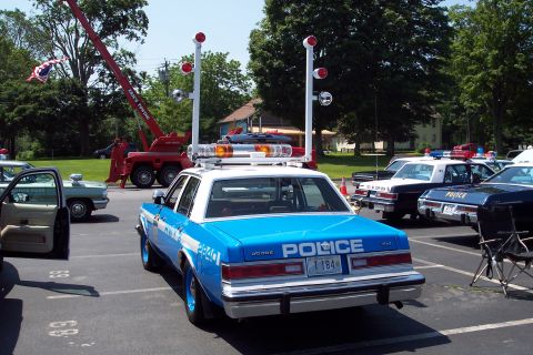 2001 Ford Crown Victoria - Rear view of a Dodge police car with a light bar and antennas, parked outdoors.
